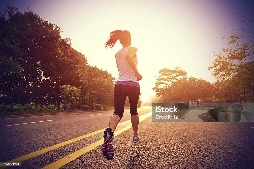 Frauen läuft auf der Straße am frühen Morgen - Lizenzfrei Rennen - Körperliche Aktivität Stock-Foto