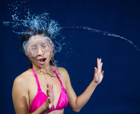 A young Asian girl catching water  against a blue background