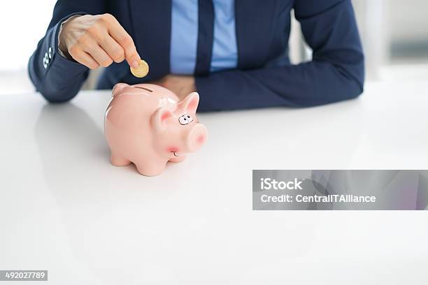 Closeup On Business Woman Putting Coin Into Piggy Bank Stock Photo - Download Image Now