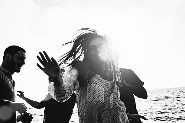 Group of multi-ethnic friends dancing on the beach Group of multi-ethnic friends dancing on the beach. black and white beach stock pictures, royalty-free photos & images