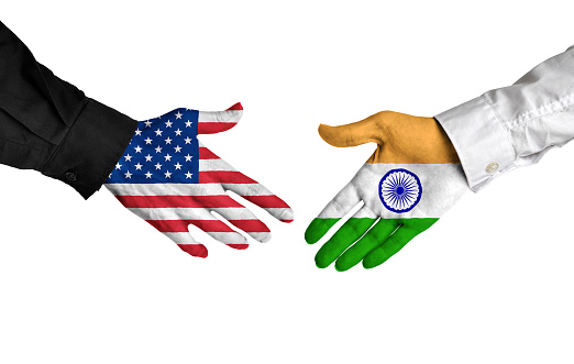 Diplomatic handshake between leaders from the United States and India with flag-painted hands.