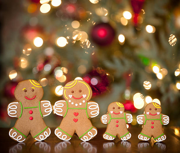 istock Ginberbread Man Family in Front of Christmas Tree Lights 492035652