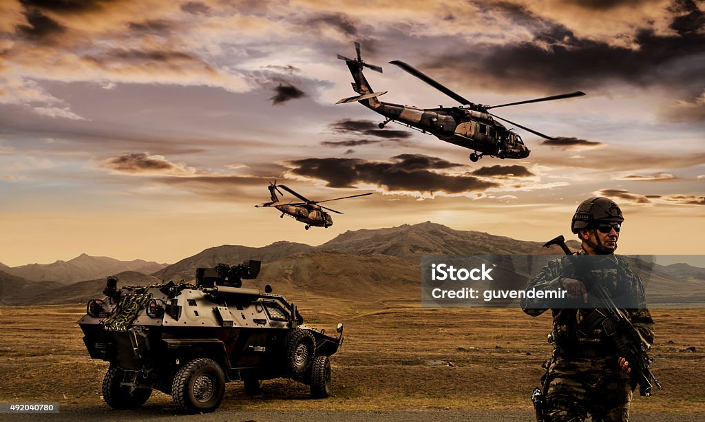 Military Operation Battlefield with a soldier, armored vehicle and flying helicopters. Military Stock Photo