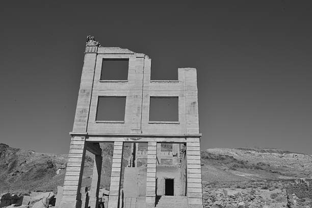 Rhyolite is a ghost town in Nye County, in the U.S. state of Nevada. It is in the Bullfrog Hills, about 120 miles (190 km) northwest of Las Vegas, near the eastern edge of Death Valley. The town began in early 1905 as one of several mining camps that sprang up after a prospecting discovery in the surrounding hills. During an ensuing gold rush, thousands of gold-seekers, developers, miners and service providers flocked to the Bullfrog Mining District. Many settled in Rhyolite, which lay in a sheltered desert basin near the region's biggest producer, the Montgomery Shoshone Mine.