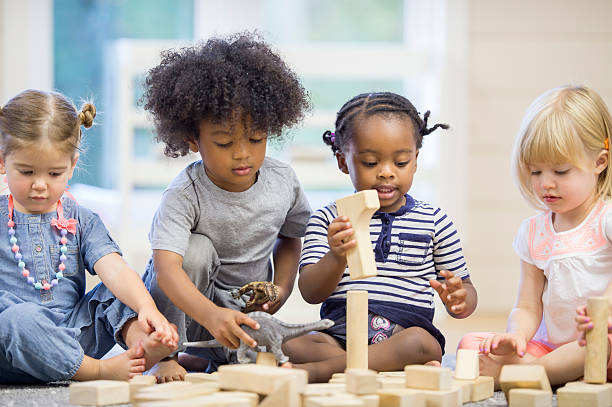 Kids Playing with Building Blocks A multi-ethnic group of toddlers are sitting together on the floor holding playing with wood blocks together. toddler stock pictures, royalty-free photos & images