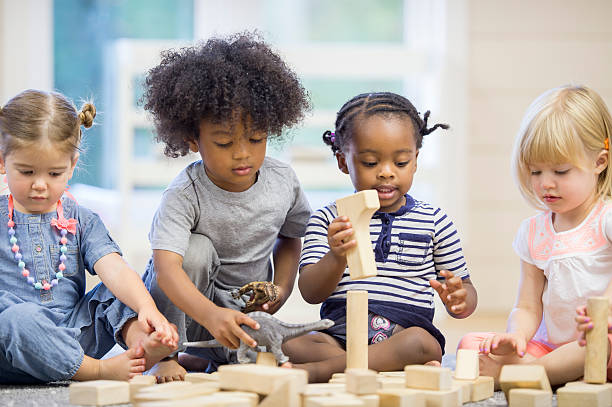 Kids Playing with Building Blocks A multi-ethnic group of toddlers are sitting together on the floor holding playing with wood blocks together. toddlers playing stock pictures, royalty-free photos & images