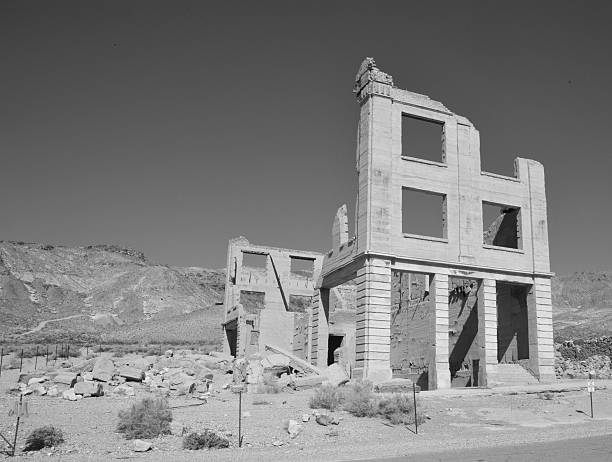 Rhyolite is a ghost town in Nye County, in the U.S. state of Nevada. It is in the Bullfrog Hills, about 120 miles (190 km) northwest of Las Vegas, near the eastern edge of Death Valley. The town began in early 1905 as one of several mining camps that sprang up after a prospecting discovery in the surrounding hills. During an ensuing gold rush, thousands of gold-seekers, developers, miners and service providers flocked to the Bullfrog Mining District. Many settled in Rhyolite, which lay in a sheltered desert basin near the region's biggest producer, the Montgomery Shoshone Mine.