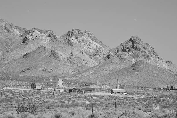 Rhyolite is a ghost town in Nye County, in the U.S. state of Nevada. It is in the Bullfrog Hills, about 120 miles (190 km) northwest of Las Vegas, near the eastern edge of Death Valley. The town began in early 1905 as one of several mining camps that sprang up after a prospecting discovery in the surrounding hills. During an ensuing gold rush, thousands of gold-seekers, developers, miners and service providers flocked to the Bullfrog Mining District. Many settled in Rhyolite, which lay in a sheltered desert basin near the region's biggest producer, the Montgomery Shoshone Mine.
