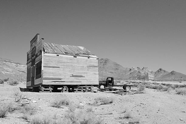 Rhyolite is a ghost town in Nye County, in the U.S. state of Nevada. It is in the Bullfrog Hills, about 120 miles (190 km) northwest of Las Vegas, near the eastern edge of Death Valley. The town began in early 1905 as one of several mining camps that sprang up after a prospecting discovery in the surrounding hills. During an ensuing gold rush, thousands of gold-seekers, developers, miners and service providers flocked to the Bullfrog Mining District. Many settled in Rhyolite, which lay in a sheltered desert basin near the region's biggest producer, the Montgomery Shoshone Mine.