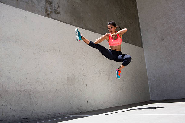 attractive brunette mujer atleta saltar en el aire - martial arts women tae kwon do black belt fotografías e imágenes de stock