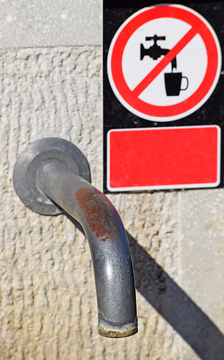 Water tap with a Non-potable sign, focus on the metal pipe