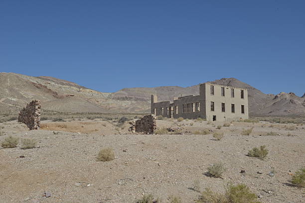 Rhyolite is a ghost town in Nye County, in the U.S. state of Nevada. It is in the Bullfrog Hills, about 120 miles (190 km) northwest of Las Vegas, near the eastern edge of Death Valley. The town began in early 1905 as one of several mining camps that sprang up after a prospecting discovery in the surrounding hills. During an ensuing gold rush, thousands of gold-seekers, developers, miners and service providers flocked to the Bullfrog Mining District. Many settled in Rhyolite, which lay in a sheltered desert basin near the region's biggest producer, the Montgomery Shoshone Mine.