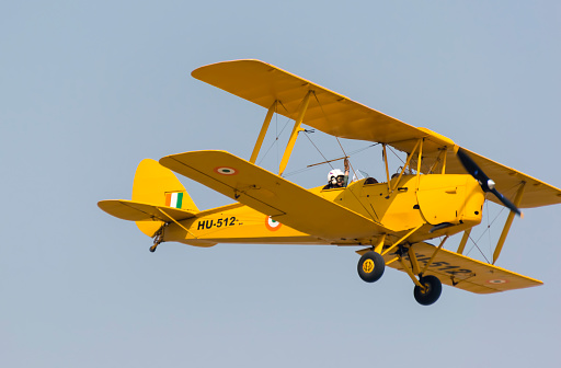Ghaziabad, Uttar Pradesh, India - October 8, 2015: A Indian Air Force Tiger Moth biplane aircraft flying at 83rd Air Force Day parade. The skilled pilot did complex midair maneuvers and daring aerial feats. The amazing aerobatics by the planes.