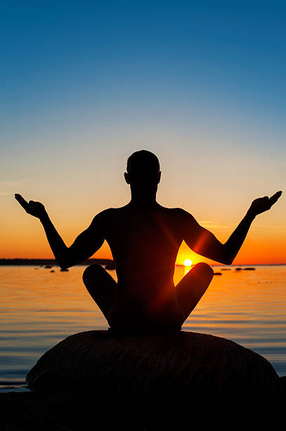 istock Meditating man silhouette on vibrant sunset background. 492046118