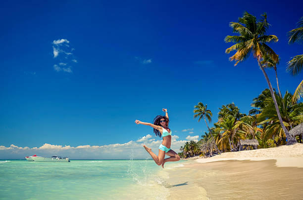 Carefree young woman jumping on tropical beach stock photo