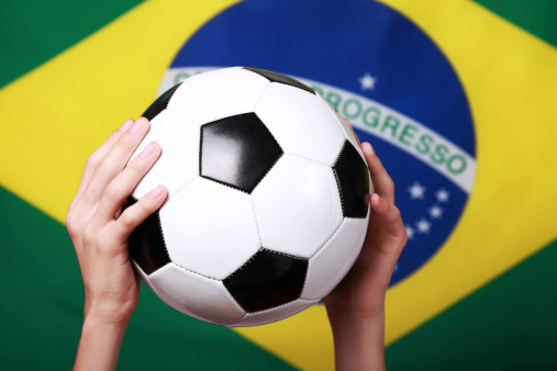 Holding a soccer ball next to Brazil flag