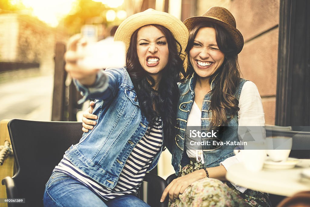 Ragazze Hipster divertendosi e prendendo selfie in un caffè - Foto stock royalty-free di Caffè - Bevanda