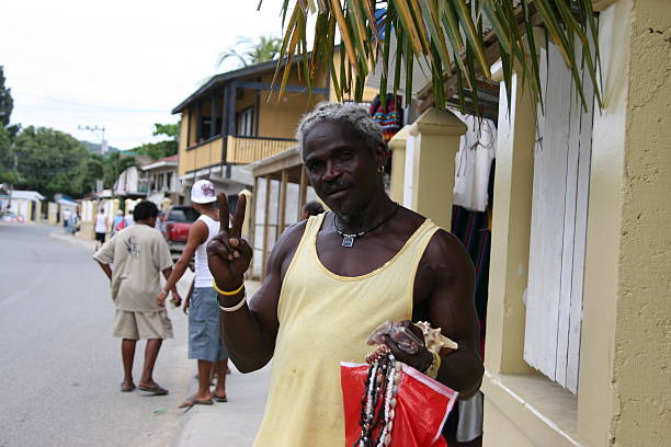 Roatan, Honduras - February 03, 2009: A black native male is selling souvenir objects to the tourists  on the street and making victory(V) sign  while posing to camera. Street sellers are very common in Roatan and cruise tourists are main customers of them.