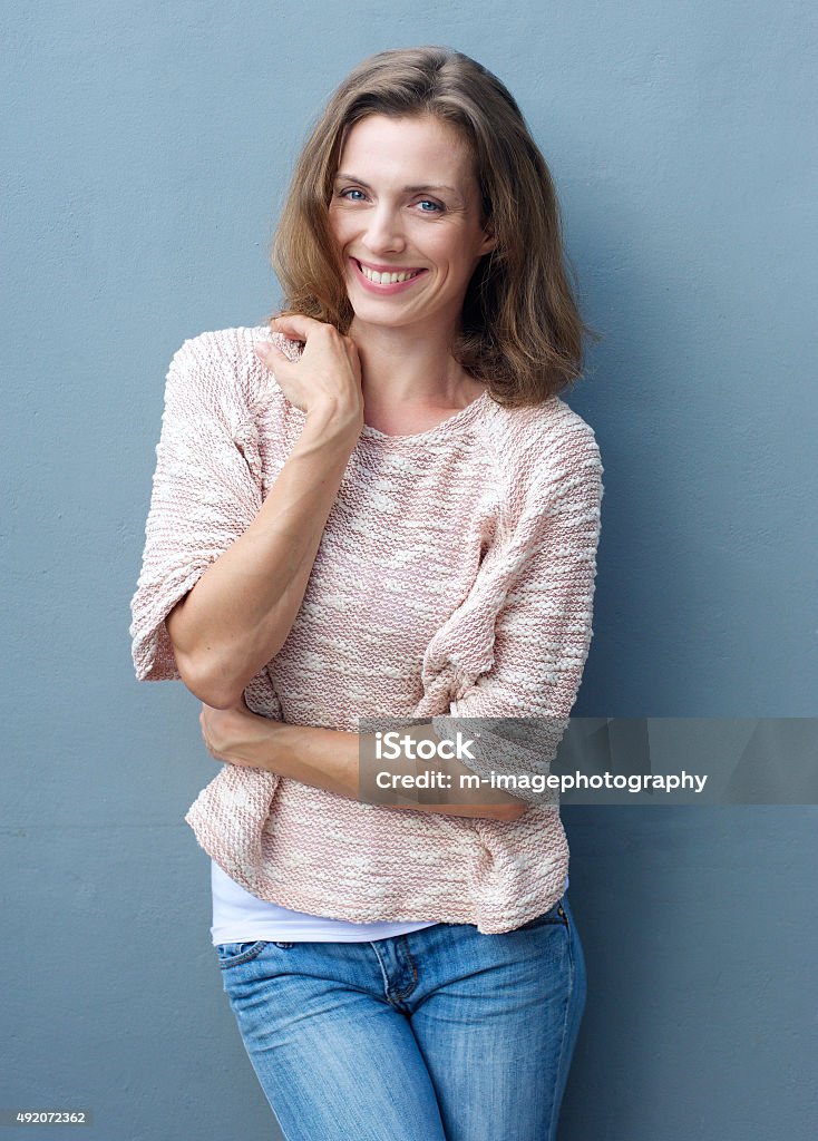 Cheerful mid adult woman smiling in jeans and sweater Portrait of a cheerful mid adult woman smiling in jeans and sweater Women Stock Photo