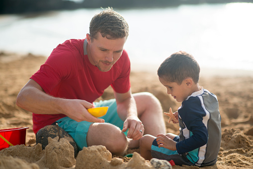 Father and son play on the beach and build a sand castle in Dubai. International Father's Day