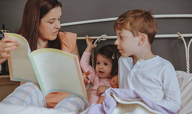istock Mother reading book to her sons in the bed 492075726