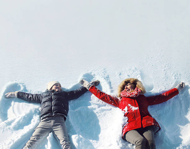 幸せな母、息子が楽しいに横たわる雪の冬の - child outdoors action freedom ストックフォトと画像