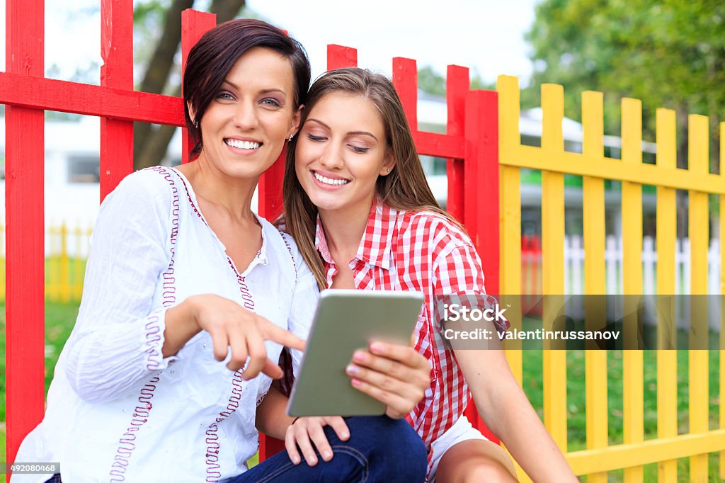 Happy girls in the park using digirtale tablet 20-29 Years Stock Photo