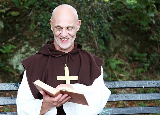 istock mature man in monk costume reading book 492081076