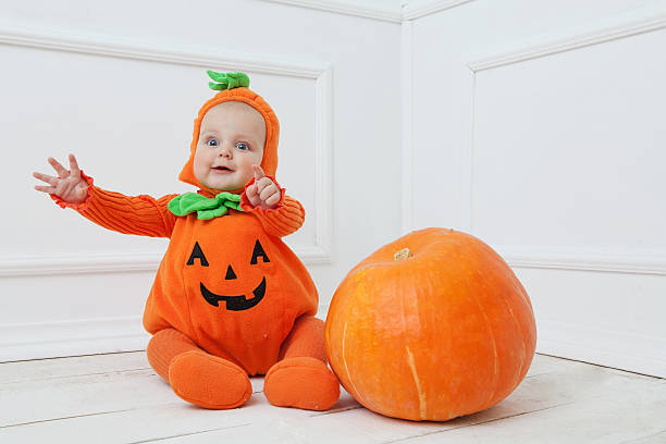 istock Child in pumpkin suit on white background with pumpkin 492082122