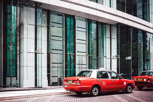 Hong Kong, Hong Kong SAR - May 6, 2014: Red taxis waiting for the clients infront of office building in downtown Hong Kong.