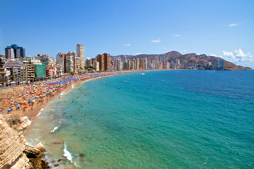 Wide angle of the Iconic hotel skyscraper skyline of Benidorm and Levante Beach, with unrecognisable people enjoying the sunshine and the Mediterranean Sea in Benidorm on the Costa Blanca, province of Alicante in Spain.