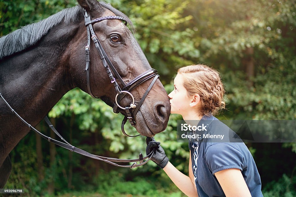 Kissing my Horse, Teenage Girl Portrait Cute teenage girl kissing her horse outdoors after a ride, looking into the horses eye. Teenage Girls Stock Photo