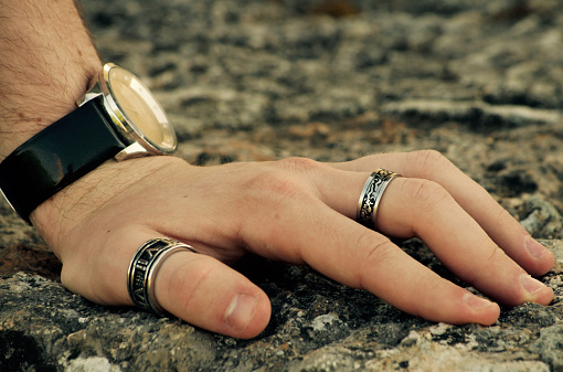 Close-up of male hand, wearing finger rings and wrist watch.