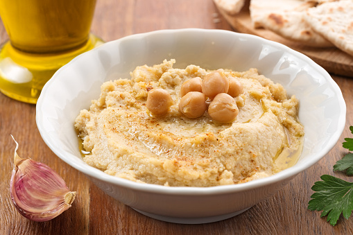 bowl with hummus, ingredients and slices of pita
