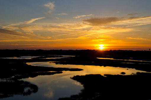 The setting sun over the Intercoastal Waterway, creates stunning colors reflected in the meandering creeks and marshland at low tide.