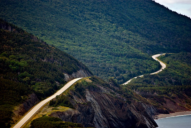 Winding mountain road Winding mountain road from the  Cape Breton Highlands National Park, Nova Scotia, Canada. Steep, forested highands on one side and the Gullf of St Lawrence on the other. cabot trail stock pictures, royalty-free photos & images