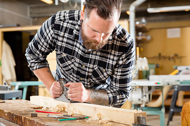 istock Carpenter work with plane on wood plank in workshop 492126622