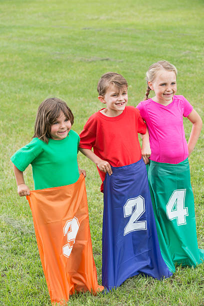 три дети делать мешок расы в парке - child playing sack race sports race стоковые фото и изображения