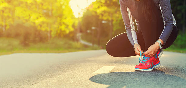 corridore femminile che contraddistinguono le scarpe prepararsi per un jogging - allacciare foto e immagini stock
