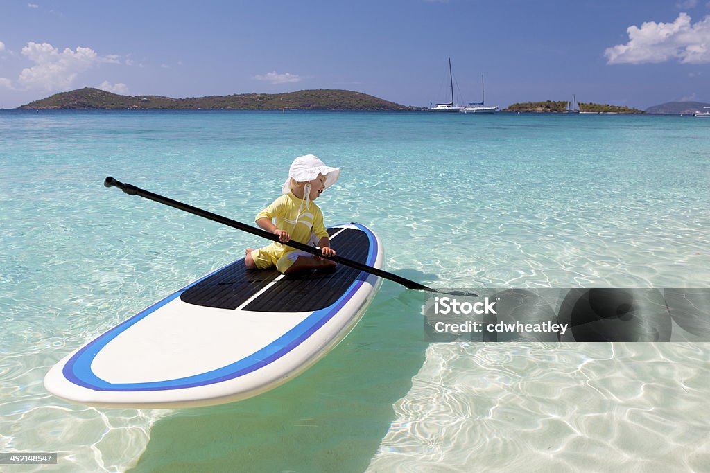 toddler learning how to paddle on paddleboard in the Caribbean toddler learning how to paddle on a stand up paddleboard at a tropical beach in the Caribbean Caribbean Sea Stock Photo