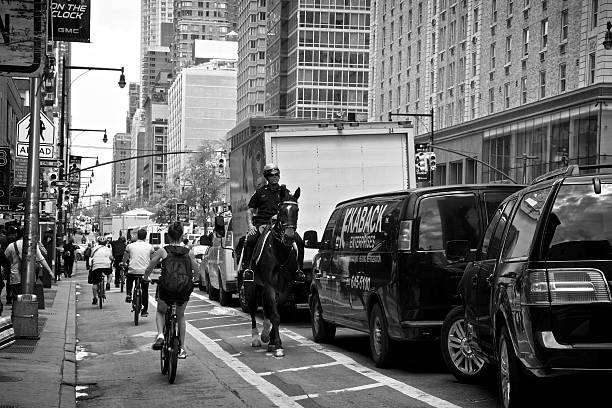 nypd berittener polizist radfahrern vorbei, midtown manhattan, new york city - caucasian three dimensional shape men sky stock-fotos und bilder