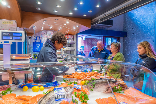 Melbourne, Australia - September 5, 2015: Shop assistant serving customers in a seafood shop in Queen Victoria Market, a historic landmark selling food and goods, in Melbourne.