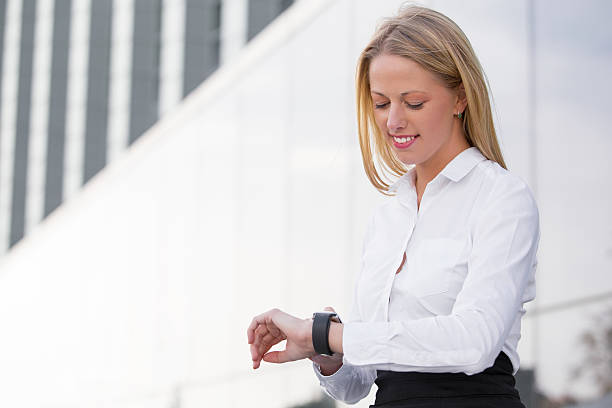 corporate business-frau aussehen und lächeln ansehen - checking the time watch women looking stock-fotos und bilder