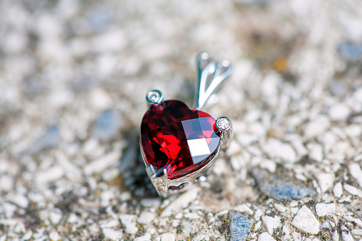 Heart shaped pendant with ruby and little diamonds on the stone background