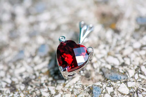 Heart shaped pendant with ruby and little diamonds on the stone background