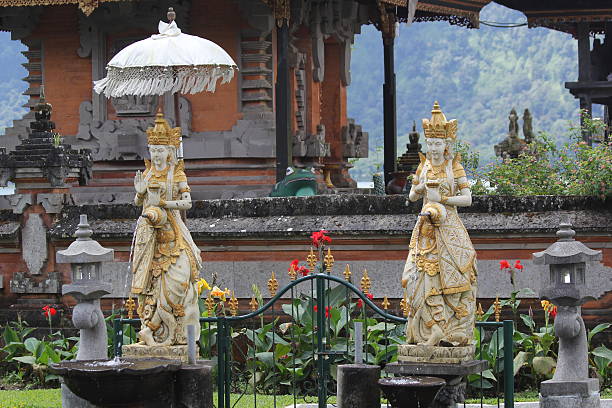 At Ulun Danu Bratan Statues grace the exterior of Ulun Danu Bratan, a Hindu temple which appears to float on the Waters of Lake Bratan in Bali, Indonesia. floating temple in lake bedugul bali stock pictures, royalty-free photos & images