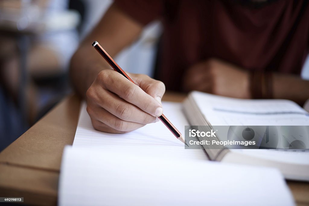Setting the page on fire with some hard work Closeup shot of a young man writing on a note pad Educational Exam Stock Photo