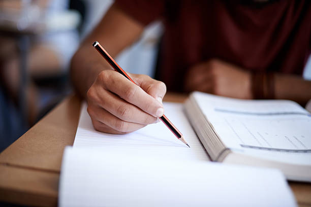 Setting the page on fire with some hard work Closeup shot of a young man writing on a note pad student desk stock pictures, royalty-free photos & images