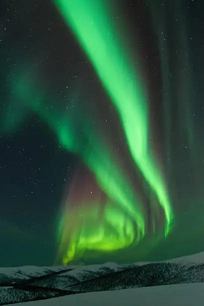 Aurora Borealis with snow covered mountain tops in winter