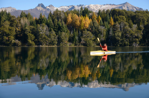 Photo of a mid adult man kayaking on down the river on a beautiful autumn day